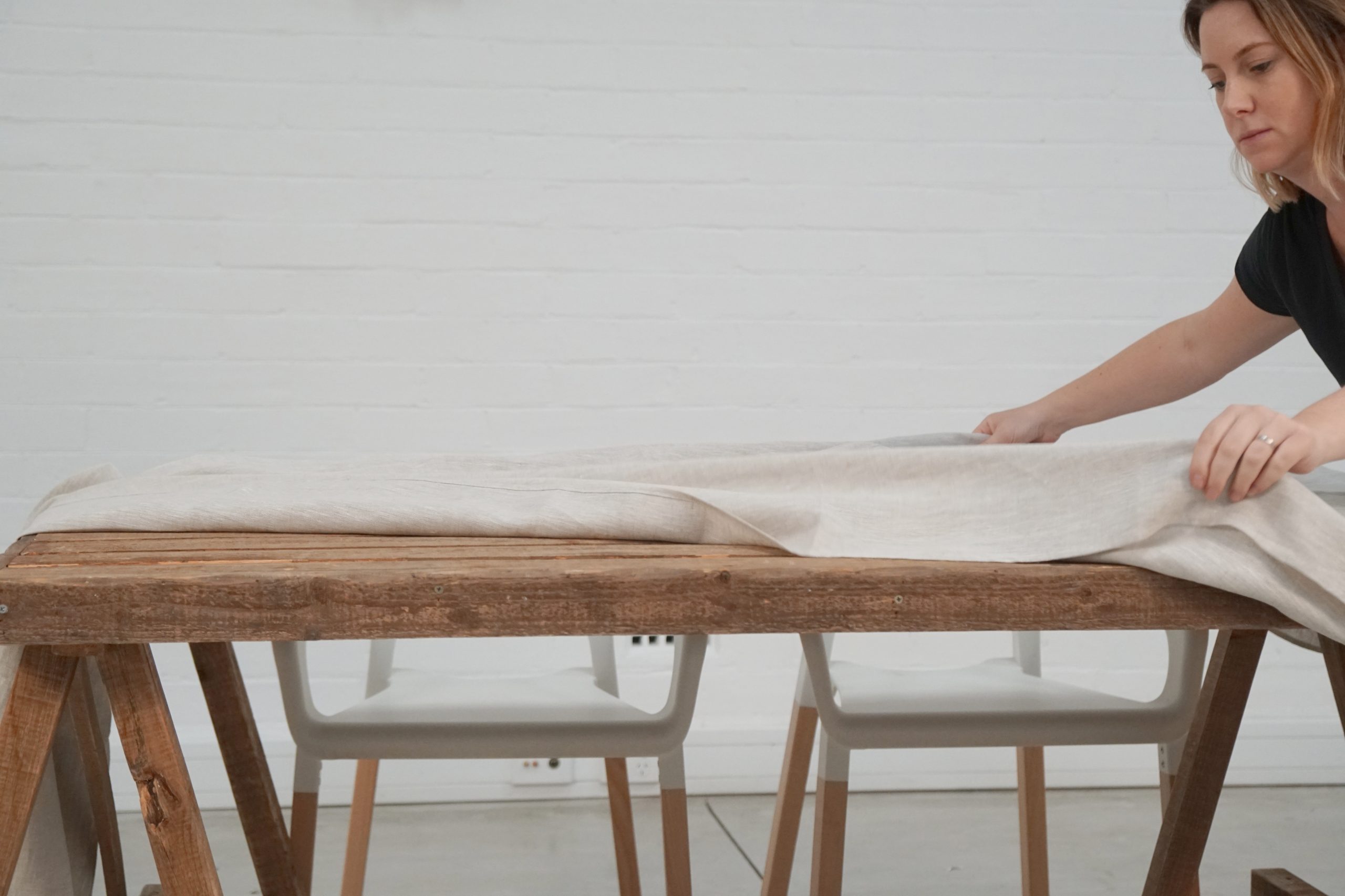 stylist laying out linen table cloth on table 